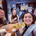 Sayani Gupta Instagram - The best part about travelling is you meet people and make new friends. The best part about travelling alone is you always go with your instinct make decisions that only you could have made. As my 18 day trip comes closer to the finish line.. I am bathed with love and warmth I was fortunate enough to gather.. from strangers.. people I will never meet in my life perhaps.. but we still managed to share some smiles, joy & candour. The woman who was helping me at the duty free at Frankfurt heard I had been to Vienna and turns out, is a western classical singer &tutor & performs regularly at both Vienna &Prague.We bid goodbye with the hope that one day, I can watch her perform.If we ever meet..over the rainbows. I told her I wanted hot food and she pointed me to her favourite joint next door to the duty free. There, at the counter, I meet an Indian gentleman who has been there for 30 years. We spoke in Hindi and laughed a lot while he made me some sandwich and coffee. I take the sandwich and coffee and find the entire place packed, with only one table with one seat left with a young girl sitting and waiting for someone. I ask her if the seat was taken and she offers it to me. Before I sit down even, she asks my name and introduces herself. A minute later, we are joined by her twin sister and mother and what could have been a lonely meal at an airport, turns out to be one of the most wholesome conversations of the whole trip. Sometimes you meet people and you feel you could be friends with them forever. This trio is one such. They convinced me to come to Norway, where they are from.. and gave me this special Norwegian chocolate. The girls who are turning 18 next week giggle and say it is the best chocolate in the world. The tag line says a ‘small piece of Norway’. Well I believe them completely. We hugged goodbye only with hopes of meeting in Norway next winter and watching the Northern Lights together.🤞🌸 This is just a snippet of some incredible people I have met on this trip. Today in this war torn world, what still unites all of us is humanity. And if you really see it up close, we are not very different from each other after all. @emilie_g.s 🌸