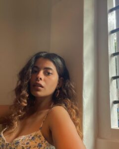 Anisha Victor Instagram - I love looking out of the window… I could do it for hours.. and it may seem like a colossal waste of time to many but it brings me peace. A short meaningful pause in the chaos of the city( same AQI but still helps).
I’m running at hundred miles per hour… okay not literally 100 miles/hour but you get the picture. The path is uneven, might even hit my toe against a rock sticking out of the ground, the coconut just about hanging on to its last fibre misses you by a second or maybe not, a gust of wind brings with it some sand ready to make my eye a temporary habitat (and if it has to be… let it be my left eye God! I use the right one to shoot). The little insect aims straight for the eyes or the nose or the mouth and that’s my first meal of the day. The little pebble… a teeny tiny microscopic pebble in my shoe! Do not underestimate it. You know the feeling right! It’s not exactly an itch you can’t scratch…you can take off your shoe and ….well just scratch your foot and take the invincible pebble out but wouldn’t it be nice to go just one day without that happening.
The crow pooped on my shirt but I’m still running because at least it didn’t get my hair this time, no reason for me to stop now when some detergent and water can take care of it later. And of course you’re going to encounter a curve ball… and I’m not taking metaphorically here;an actual curve ball. Well, what was I expecting…I’m on a track in a Cricket field. But I keep running. I see my smartwatch and I stop to quench my thirst. Luckily I have a bottle of sweet sweet water on me. Now back to running again…and if you still think it’s about running… The water bottle is the window. 🪟 Fin.