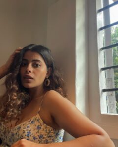 Anisha Victor Instagram - I love looking out of the window… I could do it for hours.. and it may seem like a colossal waste of time to many but it brings me peace. A short meaningful pause in the chaos of the city( same AQI but still helps).
I’m running at hundred miles per hour… okay not literally 100 miles/hour but you get the picture. The path is uneven, might even hit my toe against a rock sticking out of the ground, the coconut just about hanging on to its last fibre misses you by a second or maybe not, a gust of wind brings with it some sand ready to make my eye a temporary habitat (and if it has to be… let it be my left eye God! I use the right one to shoot). The little insect aims straight for the eyes or the nose or the mouth and that’s my first meal of the day. The little pebble… a teeny tiny microscopic pebble in my shoe! Do not underestimate it. You know the feeling right! It’s not exactly an itch you can’t scratch…you can take off your shoe and ….well just scratch your foot and take the invincible pebble out but wouldn’t it be nice to go just one day without that happening.
The crow pooped on my shirt but I’m still running because at least it didn’t get my hair this time, no reason for me to stop now when some detergent and water can take care of it later. And of course you’re going to encounter a curve ball… and I’m not taking metaphorically here;an actual curve ball. Well, what was I expecting…I’m on a track in a Cricket field. But I keep running. I see my smartwatch and I stop to quench my thirst. Luckily I have a bottle of sweet sweet water on me. Now back to running again…and if you still think it’s about running… The water bottle is the window. 🪟 Fin.