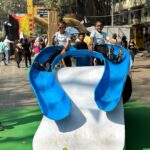 Kanchi Kaul Instagram - This February Sunday is a permanent mark on our calendars, every year!!! The atmosphere of seeing so many artists come together to present some really cool , beautiful , out of the box art installations in the most historic part of the city on the roads, out in the open , is always a pleasure and this year was no different. Pepsi cola for 50 paise outside school was my version of junk joy in my childhood. Never would it have crossed my mind that I would repeat that with my boys decades later and enjoy it even better 😀 This years theme was “ past forward” and of course had a lot to do with sustainability . To get into somebody else’s mindset into creating an art piece is an amazing journey and learning in itself. Something every child, every human should be exposed to. The childrens museum had some wonderful art exhibits put up by various schools around the city , all put in their collective , artistic and sustainable efforts for everyone to experience . Sitting in the open , listening to stories, surrounded by other kids, grasping it all in ❤️‍🔥 Walking through a museum with stuffed animals , used for research and study, we learnt so many new things including that this art is called #taxidermy . The day ended with a carnival at the derby. The beautiful sport of horse racing, (thank you dad 💖) learning about horses , their behaviours, their track records,how they train, and show off that insane horse power, so majestically. Just marvellous!!!! Although all exhibits were outstanding , Slide 7 really resonated with us …. Footwear is something constant throughout our life journey just like lifes highs and lows . coming down the slide is always a joyous moment, so in life’s journey, even when we go through the low phases , let us feel like we’re going down the slide and enjoy even that so that we learn some thing out of the experience and come out better from it “सुख” so much to be thankful for, always! #onelife #happydays #makethemostofit #peace #explore #art #artfestival #kalaghoda #derby #horseracing #carnival #theadventuresofAI #neveradullmoment #thebeautyofeverything #gadgetfreechildhood #grateful