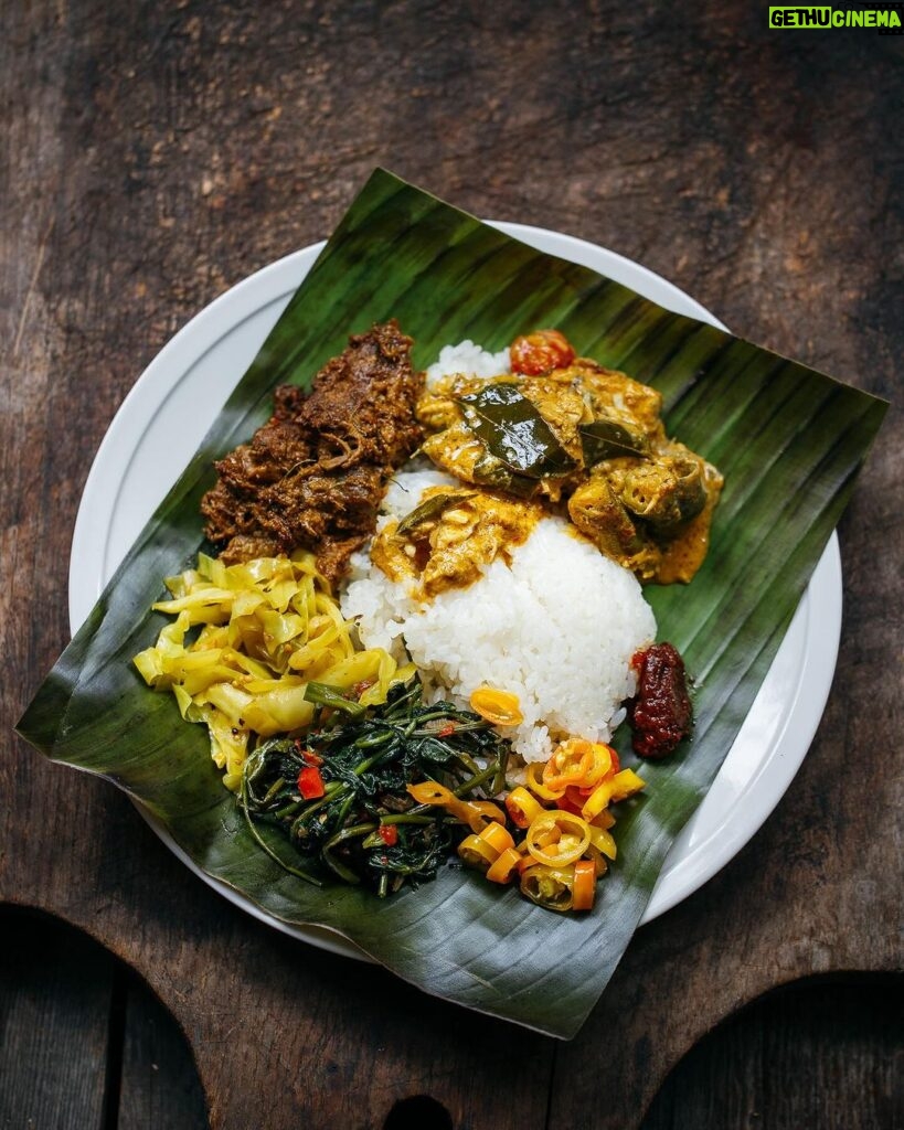 Adam Liaw Instagram - Yesterday I posted a picture of rendang, but I think it’s important to give those kinds of dishes context. I almost never make rendang on its own. It’s usually a celebratory food so there are plenty of other dishes that go around it like this plate of nasi kandar (or banana leaf). To make a meal like that takes a bit of balancing. Rendang the way I make it is rich, heavy, a little spicy (though not overly so) and kind of bittersweet in its taste profile. It would be overwhelming to have a meal of just that, so balance that I will always make something sweet and sour, in this case pickled Xinjiang chillies. There’s also a sour wild barramundi and okra curry. A mild dish of cabbage fried with turmeric and mustard seeds, a strongly savoury and fragrant kangkung belacan and there was also some fried chicken wings, and deep fried slices of bitter gourd and eggplant for both the texture and bitterness (not pictured). Each of these dishes brings something to the overall meal that combines for something much greater than each individual part.   It doesn’t get the same lens passed over it, but I think preparing a meal like this is as sophisticated an intricate as Japanese kaiseki or formal Chinese banqueting. In kaiseki the “rules” combine ingredients from the mountains, seas and forests cooked in different styles from steamed to fried to grilled. Chinese banqueting will follow mild dishes with stronger ones, steamed with fried etc. in the pursuit of balance. It’s all the same process of balancing that goes into preparing a good meal. I really think I should write a book about it because it’s something prevalent in almost all Asian cuisines, but not often discussed when those cuisines make it to the West.