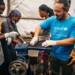 Adam Liaw Instagram – This is the UNICEF-supported #GreenGirls initiative where young women from #Sobel produce ecological charcoal from collected waste. 

We often think of the effects of climate change first impacting low-lying island nations, but #Sobel is a camp for more than 6000 Burundians who have been displaced because of extreme flooding caused by climate change.

Climate change is already having a big impact on Burundi, from increasing frequency of extreme weather events like flooding, to decreased agricultural yields caused by prolonged rainy seasons.

The Green Girls program an ingenious multi-dimensional solution to may of the problems facing these climate refugees. 

Firewood collection is a task usually performed by young women, who may have to walk for hours to find appropriate firewood. This exposes them to a high risk of sexual assault, and firewood collection contributes to deforestation. 

By producing ecological charcoal the girls don’t have to search for firewood, protecting them from potential assaults, and it also reduces deforestation and provides them with an additional source of income from the sale of surplus charcoal. An ingenious solution to a multi-dimensional problem.

It was fabulous to see this initiative first-hand, chat with the girls and play with many of the kids from Sobel.