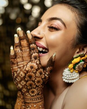 Arjun Kamath Instagram - It was the day of her mehendi, and @lakshmiambarish  had been patiently getting her hands painted while her loved ones were immersed in merriment. In the moment of freedom following the hours of being anchored, she let out a peal of laughter at some inside joke. At the time, the sun was setting outside her home and it appeared that her smile had taken over the responsibility of lighting up the room. That’s when I photographed this candid moment, capturing the ebullient charm of the free-spirited bride. Shortly after, I found myself thinking how beautiful it is to be lost in a moment of love and happiness when everyone you cherish is right by your side.

#CapturedOnCanon with a Canon EOD 5D Mark IV 

Lit with a @profotoglobal B10
@srishtidigilife @canonindia_official 

Makeup @vikrammittal5 
Hair @awon.wungkhai 

#arjunkamathphotography #bride #happy #portait #laughter #wedding #weddingphotography #photography #eosmaestro #mentorsinfocus #weddingsutra #wedmegood #photobugcommunity #photobug #bridesofindia #junebug #mywed