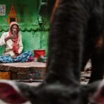 Arjun Kamath Instagram - This is a city where peace and chaos meet. Where ashes rise, and virtues breathe. Her streets are coloured with stories untold, Some sights to ponder and some to behold. And no matter how inward you go, how deep you dive. You’ll forever find treasure but never arrive. Varanasi, to me, is a city that never ends. It is as if the city’s stories, people, events, and mysteries have been playing an ages-old game of tag– always being passed on but never coming to an end. On my recent visit, I had the chance to rise early on with the city and make myself a part of its humdrum. On a dewy Wednesday morning, I awoke at 4:30 in the morning, looking forward to the soothing boat ride from Dasashwamedha to Assi Ghat. A serenading hour in the boat and a blissful arati later, I found myself in the winding gullies just close to the Manikarnika Ghat. With a choice of a new path after every dozen steps, Varanasi unfolds slowly and amusingly in these serpentine streets. I admired the soft light that painted the morning tender with a left turn here and a right turn there. The locals chattered away about their mohallas and the affairs of the city, pausing every once in a while to relish the ring of a temple bell somewhere. An ever-changing cluster of cows, street dogs, and fragile-looking two-wheelers kept me company as I walked without a motive, simply taking in the distinct way of life that Benaras is known for. At one of these many turns, I came across this gentleman sitting on a tiny stone porch, sipping his morning tea without a care for the world. In the chaos of the city’s everyday events, he seemed to have built his own pocket of peace. And at this sight, I couldn’t help but admire the character on his face and the textures and colours that enveloped him. As I took hold of my camera to take a picture of him, an unbeknownst cow happened to walk right into the frame, as if quietly claiming her presence. Smiling, I thought how perfectly this captured the raw and free-spirited essence of Varanasi and clicked the shutter button on my camera. #CapturedOnCanon with a @canonindia_official EOS R5 with a RF 24-70mm F2.8 Lens #arjunkamathphotography #varanasi #portrait #india Varanasi, India