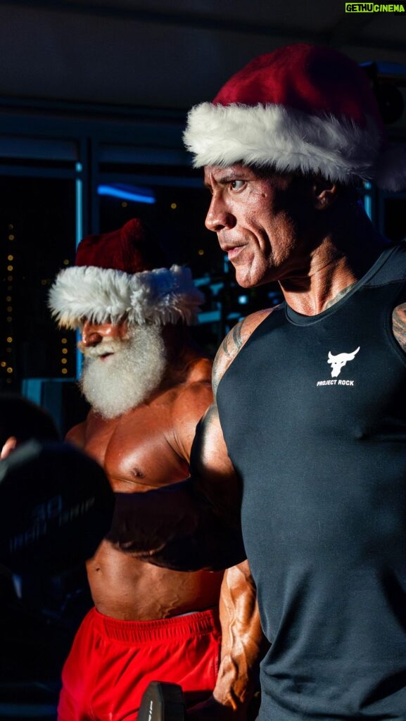 Dwayne Johnson Instagram - Twas the night before Christmas and it’s a Santa ➕ Dwanta family tradition 🎅🏾💪🏾🎅🏼 Every year, Dwanta & Santa clang and bang, getting Santa swoll as f*ck for his big trip around the world 🛷 🌎 but this Christmas he’s rocking my brand new FIRE RED @ProjectRock’s PR6s 👟 🔥 Big shout to my boy @mike_ryan_celebritytrainer aka Santa🎅🏼 who’s one of my best friends and greatest training partners. He’s a BEAST and just as filthy as I am - so our training sessions are intense, hard core and full of f*cked up laughs 😈😂💪🏾 Merry Christmas my friends and may you never get herpes from an Elf 🧝🏾😂 Love, Dwanta 🎅🏾 Enjoy the kicks! Link in my bio ☝🏾👟🔥