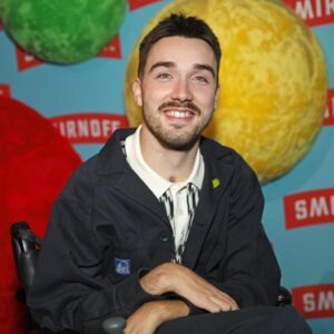 George Robinson Instagram - #ad I had a great time celebrating the launch of @smirnoffeurope WE DO US Live. While I love a good party, it’s way better when everyone can be a part of it. That’s why making nightlife more accessible is so important. @smirnoffeurope and Disability-led organization @tiltingthelens are working together to improve accessibility by supporting the Disabled community in clubs, bars and pubs - more to come! To everyone involved - thank you for such a fabulous night and showing easily it can be done.

************

Image Description: George Robinson is a white, masc wheelchair user. He has green eyes, cropped, dark hair, a moustache and dark stubble along his jawline. He is wearing a dark jacket and chinos and a white and black houndstooth polo shirt. He is wearing thick, textured brown socks and black leather shoes. On his lapel he has a small light green pin. He is positioned in front of a sky blue branding board, with the red and white Smirnoff logo repeated all over and red, green and yellow spheres covered in felt as a decoration. He is smiling for the picture and is at the Smirnoff ‘We Do Us Live’ event, celebrating accessibility in music. The event took place on 29/11 at 26 Leake Street in London.