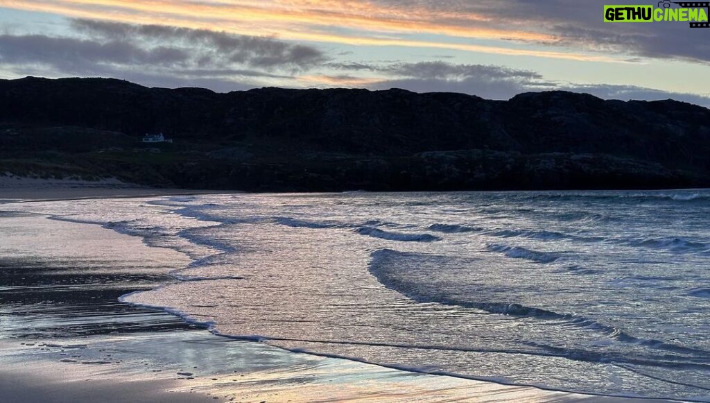 Louise Brealey Instagram - We drove west along the north coast of Scotland into the dazzle of a sunset and made it to the beach just before the sun slipped down behind a band of cloud. There was a smushed marigold on the tide line. I walked the quarter mile to our bit of the beach, where a scree of giant pebbles meet the sand. On my phone is a picture of mum sat here with a towel on her head. I put the marigold on the rocks. The Mexicans call it the flower of the dead and use its bright colours to guide the spirits of their lost ones to their shrines on the Dio de los Muertos. I ran my fingers through the fine white sand and let the sea and the sky do their thing.