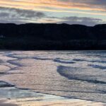 Louise Brealey Instagram - We drove west along the north coast of Scotland into the dazzle of a sunset and made it to the beach just before the sun slipped down behind a band of cloud. There was a smushed marigold on the tide line. I walked the quarter mile to our bit of the beach, where a scree of giant pebbles meet the sand. On my phone is a picture of mum sat here with a towel on her head. I put the marigold on the rocks. The Mexicans call it the flower of the dead and use its bright colours to guide the spirits of their lost ones to their shrines on the Dio de los Muertos. I ran my fingers through the fine white sand and let the sea and the sky do their thing.