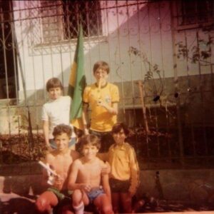 Mário Marra Instagram - Quando a Copa entrou na sua vida?
Tenho lembranças ainda mais antigas que a da foto, mas foi a Copa de 82 que mais mexeu com a minha vida.
Era a época de decorar a Rua Guaranésia com bandeiras, pintar o chão, jogar bola driblando paralelepípedos e contar com algum colega atento que avisava quando o ônibus da viação Andrade Costa apontava a esquina. Víamos os jogos na casa do meu tio e era lindo estar ali com meus primos.
Os dias eram incríveis. Mesmo pequenos tínhamos nossas dores e ausências, mas a mobilização em torno da Copa anestesiava tudo por um tempo. Parece que nossos pais também esqueciam de tudo e o objetivo era um só. 
O tempo se encarregou de mudar prioridades, olhares e de nos embrutecer por dentro, mas aqueles dias daquela Copa são até hoje bons, quentes e amorosos.
Que grande lembrança!
Quando a Copa entrou na sua vida?