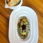 Michael Voltaggio Instagram - retro avocado toast… the avocado is confit in the oven in avocado oil with lots of onion and garlic. The “pit” is a sphere of black garlic vinaigrette