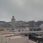 Vera Kolodzig Instagram - Dia 13: Conhecida como a “Cidade Ventosa de África”, Essaouira atrai muitos kitesurfers durante o ano inteiro, no entanto há muito mais do que o areal a perder de vista, ou o cenário do Game of Thrones. O sultão Mohammed Ben Abdallah instalou-se aqui no século XVIII e contratou um arquitecto francês para desenhar uma cidade no meio do vento e da areia onde nada existia antes. Originalmente chamada de Mogador, o sultão mudou o nome para Essaouira que significa “bem desenhado”, com a sua mistura única de estilo marroquino e europeu. Chegámos ontem à noite, já com mesa marcada num restaurante sugerido por um amigo, onde reencontrámos a amiga que fizemos em Tarifa na noite antes de iniciarmos a viagem. Acabámos num nightclub onde uma troca de olhares nos levou a conhecer os melhores guias que podíamos desejar. A manhã de hoje foi na praia, com um mergulho salgado para lavar a alma. Surgiu então a possibilidade de ir à lota comprar o marisco mais fresco que alguma vez vi. Ao passar o arco do kasbah parecia todo um novo mundo, com as embarcações já atracadas e dezenas de pessoas a vender o que pescaram de manhã, enquanto as crianças se atiravam dos muros da fortaleza para o mar. Foi neste momento que decidi que se há locais para abrir excepções à minha habitual dieta, este é um deles, ainda assim mantendo os meus princípios - saúde e sustentabilidade. Duas lagostas, um caranguejo, camarões e uma conserva caseira, por 500dhr negociados pelos nossos amigos marroquinos. Depois levaram-nos pelo labirinto da medina até um terraço onde apenas famílias locais se deliciavam. Entregámos as nossas compras, e uma hora depois tínhamos uma mesa repleta das mais incríveis iguarias, por mais 60dhr - o custo do “aluguer” de um espacinho na grelha. Uma experiência que ficará para sempre nas nossas memórias e nos nossos corações, já com uma pequena nostalgia de uma despedida para breve. Amanhã começamos a subir, de barriga cheia e inshallah sem caganeira! . . . #roadtrip #morocco #essaouira #localexperience #instatravel #seafood Essaouira - Mogador - الصويرة