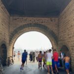 Vera Kolodzig Instagram - Dia 13: Conhecida como a “Cidade Ventosa de África”, Essaouira atrai muitos kitesurfers durante o ano inteiro, no entanto há muito mais do que o areal a perder de vista, ou o cenário do Game of Thrones. O sultão Mohammed Ben Abdallah instalou-se aqui no século XVIII e contratou um arquitecto francês para desenhar uma cidade no meio do vento e da areia onde nada existia antes. Originalmente chamada de Mogador, o sultão mudou o nome para Essaouira que significa “bem desenhado”, com a sua mistura única de estilo marroquino e europeu. Chegámos ontem à noite, já com mesa marcada num restaurante sugerido por um amigo, onde reencontrámos a amiga que fizemos em Tarifa na noite antes de iniciarmos a viagem. Acabámos num nightclub onde uma troca de olhares nos levou a conhecer os melhores guias que podíamos desejar. A manhã de hoje foi na praia, com um mergulho salgado para lavar a alma. Surgiu então a possibilidade de ir à lota comprar o marisco mais fresco que alguma vez vi. Ao passar o arco do kasbah parecia todo um novo mundo, com as embarcações já atracadas e dezenas de pessoas a vender o que pescaram de manhã, enquanto as crianças se atiravam dos muros da fortaleza para o mar. Foi neste momento que decidi que se há locais para abrir excepções à minha habitual dieta, este é um deles, ainda assim mantendo os meus princípios - saúde e sustentabilidade. Duas lagostas, um caranguejo, camarões e uma conserva caseira, por 500dhr negociados pelos nossos amigos marroquinos. Depois levaram-nos pelo labirinto da medina até um terraço onde apenas famílias locais se deliciavam. Entregámos as nossas compras, e uma hora depois tínhamos uma mesa repleta das mais incríveis iguarias, por mais 60dhr - o custo do “aluguer” de um espacinho na grelha. Uma experiência que ficará para sempre nas nossas memórias e nos nossos corações, já com uma pequena nostalgia de uma despedida para breve. Amanhã começamos a subir, de barriga cheia e inshallah sem caganeira! . . . #roadtrip #morocco #essaouira #localexperience #instatravel #seafood Essaouira - Mogador - الصويرة