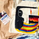 André Gabeh Instagram - Minha gente! Socorro! Abri o kit que recebi ontem da @meleproducoes e estou todo urinado! Todo torto e afofalhado. Simplesmente tem uma BOLSA PINTADA A MÃO PELO POLIFÔNICO DODECAÊDRICO E AFROQUANTICO @ronaartista ! Gente! Vou transformar em quadro! ARTE PURA! Que coisa linda!!! Tem adesivo com arte do também maravilhoso, único e personalíssimo @tarsotabu E pra acabar com meu coração tem um postal com mensagem carinhosa escrita à mão, latinha de moscatel espumante e CACHAÇA MAGNÍFICA. MEU DEUS. ME ENGRAVIDA MELÉ! Essa produtora maravilhosa e incrível vai botar no mundo uma tarde gloriosa de Jazz no dia 28 de Janeiro e eu vou. Vamos? Vamos, né? Pelo amor de Pelamor!. JAZZIN no PARAÍSO VERTICAL. P.s: A música não tem nada a ver com o evento, mas hoje é dia de Oxóssi e fica aqui a homenagem. Vamos! #arte #art #music #musica