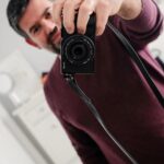 Diogo Beja Instagram - Olá, eu sou o Diogo e sou um cromo. 🤓 E picuinhas também. Picuinhas ao ponto de recear que uma ínfima molécula de qualquer coisa possa danificar a minha câmara principal. Por isso, ela fica em casa mais vezes do que devia. E também por isso, andava já há algum tempo à procura de uma câmara pequena, com a qual não me preocupasse tanto, mas que me garantisse qualidade de imagem e as cores que tanto adoro na minha Fuji. A incrível Fujifilm X100V ficou fora de questão, porque o preço é meio obsceno e a alta e inesperada procura pela mesma criou listas de espera em todo o mundo - desisti logo aí da ideia, porque não sou hipster. 😁 Foi aí que entrou em acção a Fuji X-M1, uma câmara com mais de 10 anos, que é o compromisso perfeito entre portabilidade, qualidade de imagem e picuinhice do dono. 🙈 Quando encontrei uma em muito bom estado, não pensei duas vezes. E não precisei de pensar mais quando chegou a altura de escolher uma “strap”, para a poder realmente levar para todo o lado. Recorri, como recorro sempre, ao excelso mestre artesão Paulo aka @coordamestraps que, com o seu saber e paciência infinita, executou na perfeição a correia de couro que imaginei na minha cabeça. A X-M1 até parece uma Leica. 😍 Obrigado, Paulo! (As fotos foram tiradas no closet da Mia. 😁😁) #fujifilmxpt #coordamestraps #FujiFilmXM1 #notALeica #FujifilmX100Vlovers