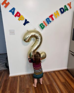 Mary Katharine Ham Instagram - This gal turned two! For those keeping count, that means we had two under two… for 9.5 months. And we’re still standing! A lot of the credit for that goes to Holly, who much like her father, has a GIANT personality and also loves a schedule. That means she sleeps. Hallelujah, can that girl sleep, from 6pm-7am, in the same room as her brother. 

When we say “bedtime for baby?” after two episodes of “Bluey,” our girl marches herself up the stairs to get her zzzzs. “Bye, guys! Bye, guys! Bye, Guggy!” (this is either doggie or Garnet, we’re not sure which) She is a woman of few words.

She says “Dad” constantly, “wow” and “Scout” and “stop” and “don’t,” usually to her bro. She has a long-running joke where I ask her to say “Mama,” and she mouths it without actually saying anything and then laughs because, let’s face it, that’s funny. But she resorts to “Mama” when she’s very sad, which isn’t often.

She is good-natured and very physical. The other day, I told her to say “please,” and I would lift her over the couch, and she was stubborn about “please” and simply hoisted herself over the couch with a ridiculous display of brute upper body strength.

She is newly into books, but her brute strength makes her the first kid I’ve ever had capable of destroying board books. She might be the most problem-solving kid I’ve had. She untied, collapsed and removed the tent pole from her little play tent in the living room while I wasn’t looking the other day, then uncollapsed it to hold up in front of me. (Meanwhile, her brother is already saying “bottle” in an effort to defend himself against her when she steals his bottle, which is often).

Watching her play is a bit like watching the velociraptors test the fences. “Clever girl.” She loves to clean (also gets that from Dad), brings her own diapers for diaper changes and throws the dirty ones away. She’s just started doing “big hugs” and will hug you and sigh and pat you on the back. Sings along with “Daniel Tiger” and loves cheese, ham, and anything I’m eating. 

She has made a lot of our lives possible the last 9 months by just being her and, boy, do we love her! Can’t wait to see her grow!