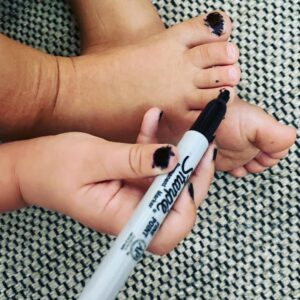 Nicole da Silva Instagram - She’s quiet, though. @sharpie #PenLicence #IfYouKnowYouKnow #Dexterity

Image Description: A small child’s hand with black nails, colours in her toenails with a black Sharpie.