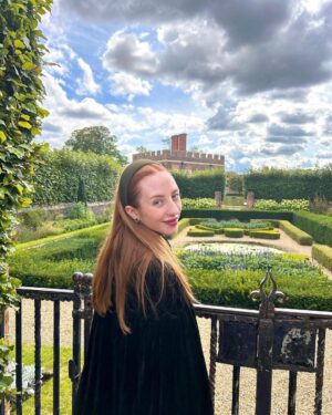 Rebecca Flint Instagram - if you can’t wear a cape in hampton court palace i’m not sure where you can 🌹?

I have always wanted to see this incredible tudor palace for myself and I was so excited to have the chance!

they had live cooking demonstrations inside the original kitchens, and we saw so many amazing tapestries and paintings… incredible day to visit!

the puff headband trend always reminds me of the French Hood so I had to wear this army green one, along with this spectacular velvet and silk cape picked up from @classiccarbootsale in the spring! My dress is vintage from Japan, and my bag is @aspinaloflondon. The shoes are @empressaustralia 🔍

Not forgetting my B necklace as an homage to Anne 🅱️❤️