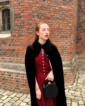 Rebecca Flint Instagram - if you can’t wear a cape in hampton court palace i’m not sure where you can 🌹?

I have always wanted to see this incredible tudor palace for myself and I was so excited to have the chance!

they had live cooking demonstrations inside the original kitchens, and we saw so many amazing tapestries and paintings… incredible day to visit!

the puff headband trend always reminds me of the French Hood so I had to wear this army green one, along with this spectacular velvet and silk cape picked up from @classiccarbootsale in the spring! My dress is vintage from Japan, and my bag is @aspinaloflondon. The shoes are @empressaustralia 🔍

Not forgetting my B necklace as an homage to Anne 🅱️❤️