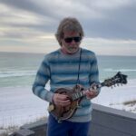 Sam Bush Instagram – Happy Holidays to all you Music Lovers.  May you enjoy the Holiday of your choice with those you choose.  With Yuletidings & gay apparel we wish y’all a very Merry Christmas 🎄🎁 
Sam, Lynn & the Sam Band Family