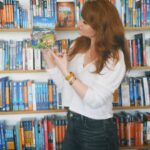 Bryce Dallas Howard Instagram – Returning to the motherland this week #Ireland 🇮🇪⁣⁣
⁣⁣
📸: @andiejjane⁣⁣
⁣⁣
[ID: Wearing a white blouse and blue jeans, BDH stands in front of a bookcase with shelves and shelves of miscellaneous travel guides. She holds the Lonely Planet guide for Ireland by her face, absolutely ecstatic about returning to Ireland after 30 years!!]