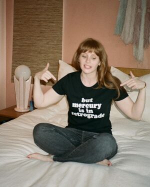 Bryce Dallas Howard Instagram - Mercury is Retrograde! In Virgo! To use the words of astrologer and writer @chaninicholas, “Good luck to us all!”⁣⁣
⁣
📸: Andie Jane (@andiejjane)⁣⁣
⁣⁣
[ID: BDH sits cross-legged on top of a fluffy white comforter. She points to her black t-shirt which reads, “but mercury is in retrograde.”]