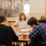 Bryce Dallas Howard Instagram - It’s #WorldTeacherDay and I can’t go without thanking the teachers/ mentors in my life who absolutely shaped who I am today and thanking the NYU students who made me a teacher in the first place 🥹 #NineMusesLab @ninemusesentertainment ⁣ ⁣ [ID: Around a big wooden table in an open classroom with twinkly lights, BDH teaches her “Making It & Mastery” course to the first cohort of NYU students in 2018]