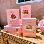 Bryce Dallas Howard Instagram - Thank you @sweetlaurelbakery for the delicious treats 💖 I never knew how soothing cake decorating could be… and next time I’ll start my design with the end in mind 😅 I hope The Great British Bake Off would be proud.⁣⁣ ⁣⁣ @laurelgallucci and @clairethomas, it’s always a joy to hang out with you and I can’t wait for Sweet Laurel to grace the shelves of our grocery stores soon! ⁣⁣ ⁣⁣ [ID 1: Living her cottage-core dreams, BDH stands between Laurel Gallucci and Claire Thomas (co-founders of Sweet Laurel Bakery) in a picturesque garden. They each hold a chocolate cake decorated with roses and raspberries.]⁣⁣ ⁣⁣ [ID 2-3: BDH twirls and shows off her new Sweet Laurel apron and canvas tote.]⁣⁣ ⁣⁣ [ID 4: A stack of Sweet Laurel Bakery’s upcoming chocolate cake, pancake, and scone mix boxes.]