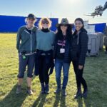 Bryce Dallas Howard Instagram - Filming on #InternationalWomensDay with these beauties was a BLAST! Plus, we wrapped early 😉⁣ ⁣ [ID: As the sun sets behind tall blue screens on a grassy field, BDH smiles as she stands next to the 1st AD, DP, and Executive after a great day on set.]