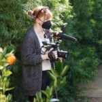 Bryce Dallas Howard Instagram - They say a director must become one with their environment 😉🌳 I’m filming my second documentary feature for @disneyplus and am very excited for you see what’s on the other side of the camera! ⁣ ⁣ For all the film techies out there, this is @canonusa’s EOS C300 — I was so lucky to be one of the first directors to test this camera back in 2011 for my short film "When You Find Me" 🚀 I absolutely love how intuitive it is to operate. 100% recommended. ⁣ ⁣ [ID: BDH in a grey cardigan, white v-neck, and black leggings becoming one with tall hedges, holding a Canon camera. 📸: @fullyjacked]