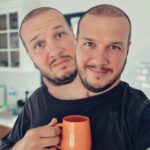 Şahan Gökbakar Instagram - Ozellikle ikinci dozdan 3 hafta sonra, beyincik soganimdan yeni bir filizlenme oldu. Once anten oldugunu ve artik 5g cekecegimi dusunup cok mutlu oldum.. ama sonra 2. Kafamin ciktigini farkettim. Başlarda birbirimize hic alisamadik. Surekli iki bogaz doyurmak, cift maske takmak ve sosyal mesafeyi korumak vs. cok zordu. Ama bu surec bana hayata bakarken "BEN" degil "BIZ" diyebilmeyi ogretti...Kuresel gucler hucre cekirdegimi bozup beni iki kafali etseler de, ayaga kalkmayi tekrar hayata tutunmayi basardim. Ileride baska uzuvlarimda cogalabilir, hazirim!! Ve Evet..!! Artik ben ve Spike (ismi spike) daha mutluyuz. Tesekkurler Bill Gates ve kuresel dostlari... oyun boyle bozulur!