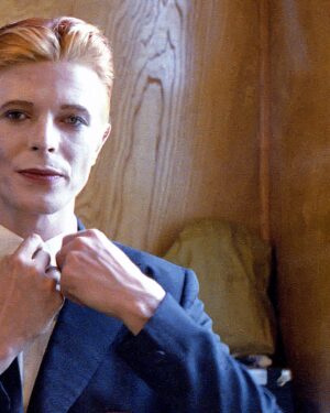 David Bowie Instagram - Not much evidence of a mirror in this first shot from 1975 of Bowie as Thomas Jerome Newton, until you look at those famous eyes.

All is revealed in the uncropped image as Geoff MacCormack is seen taking the shot in David’s changing room on the set of The Man Who Fell To Earth. 

Have you read Geoff’s book DAVID BOWIE: ROCK 'N' ROLL WITH ME?

It’s a touching account of a lifelong friendship, peppered with Geoff’s extraordinary shots of David at work, rest and play: https://bit.ly/RockNRollWithMeBook (Linktree in bio)

#BowieReflections