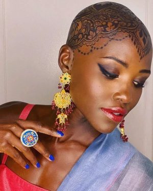 Lupita Nyong'o Instagram - THE STORY OF MY HEAD: 
I met @hennabysabeen last year at a wedding in Pakistan. She did the #HennaDesign for the bride and I was ASTOUNDED by the INTRICACY and BEAUTY of her work. There was something unique about the way she expressed herself in henna art. And I promised myself, "One day I will have a reason to work with Sabeen."
:
1.5 years later, when I got the invitation to attend the opening night of my dear friend, Mira Nair's @monsoonmusical, I was scrambling at the last minute to find something to wear. I borrowed a sari and jewelry from @mishajapanwala, the bride from Pakistan, but the look didn't feel complete...
:
And then, in the middle of the night, an image SHOT into my mind of a henna design covering my bald head!!! I could do something special and different, to celebrate the culture using the canvas readily available to me! I was so excited by the idea that I could not go back to sleep. Misha connected me to Sabeen, and we were ON OUR WAY...
:
Sabeen had NEVER designed for a head before; I had never done such a thing before either. My only prompt to her was that I wanted a widow's peak (homage to the bindhi, borla / maang tikka), the rest was ALL HER INNOVATION.  She suggested #jagua, a natural dye from the jagua fruit of South America that would be dark enough to give good contrast to my dark skin ☺️. 
:
We were both excited and terrified. What if it went wrong or looked funny??? Well, I thought, I can always wear a head wrap.... 
:
But Sabeen BROUGHT IT! We stopped now and again so that I could give her feedback because she was DETERMINED to leave me a happy client. And Sabeen was METICULOUS. She did not stop until it was perfect. When we looked at the finished head... we were both GRINNING!
:
It takes about 24 hours for the dye to really show up. And when it came in, in FULL CONTRAST the next day, I was simply MOVED. It was beautiful. It was bold and elegant; it had a point of view. We had not played it safe, and it had paid off. And I had found a new way to express myself without hair! 
:
So the moral of this story is: DARE YOURSELF TO SEEK OUT BEAUTY IN NEW WAYS. And, Sabeen, thank you for bestowing on me the beauty of your hand and history!