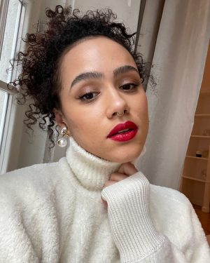 Nathalie Emmanuel Instagram - Virtual press for #LastTraintoChristmas (Out on Sky Cinema December 18th) requires snowy jumpers, red lips and bauble like pearl earrings… and hair and make up by @norarobertson_mua. 🚇🎁🎄

Jumper: @nanushka 💚🌱
Earrings: @miumiu ⚪️⚪️
