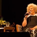 Alcione Instagram - Já está disponível, em todos os aplicativos de música, o álbum comemorativo aos 50 anos de carreira da Marrom, gravado no Theatro Municipal do Rio! (Equipe) Brahma e Secretaria de Estado de Cultura e Economia Criativa do Rio de Janeiro, através da Lei de Incentivo à Cultura, apresentam: ALCIONE 50 ANOS O show, que também está na íntegra no YouTube da @biscoitofino por 72 horas, tem direção musical de Alexandre Menezes e geral de Solange Nazareth, traz um mosaico formatado por medleys com 65 músicas das mais diferentes fases da vitoriosa carreira de Alcione: “A Loba/Ou Ela, Ou Eu”, “Sufoco”, “Meu Ébano”, “Estranha Loucura”, “Você Me Vira a Cabeça”, “Além da Cama”, “Garoto Maroto”, “Faz Uma Loucura Por Mim”, “Nem Morta”, “Gostoso Veneno” e muitas outras! Além da Banda do Sol que a acompanha por décadas, integrantes da Orquestra Sinfônica  Maré do Amanhã, dançarinos da Academia Marcello Chocolate e Sheila Aquino e da Cia. Cenarte Dimensões; além, é claro, da Estação Primeira de Mangueira, fizeram parte da gravação. O espetáculo que deu origem ao novo DVD da cantora abriu ao som eletrizante do Ilé Àṣẹ Ọbalúwáiyé Jagun, casa do Pai Celinho de Omolu, e com a voz poderosa de Maria Bethânia que estava na plateia) recitando os versos da autobiográfica "Resumo" (música de Roberto Correa e Sylvio Son). "Alcione 50 Anos" não é apenas o álbum que celebra o cinquentenário de carreira dessa artista que é sinônimo de brasilidade. Conta uma história de sucesso construída com muito trabalho e norteada por um amor extremo ao ofício. -"Cantar é ofício e paixão. E só tenho a agradecer àqueles que me auxiliaram, conduziram-me até aqui. Agradeço, principalmente, aos fãs. Sem eles não existiriam artistas", resume Alcione.