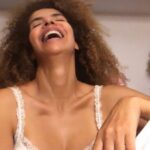 Vanessa da Mata Instagram - Era vez do silêncio no quintal de minha casa! O ingá fálico reboliço na minha face roçando, enquanto eu tomava café melado, e o ingá dependurado na mãe dele. A minha pele dura de lama branca, que eu colocava, das tantas cacheiras que eu ia, levar meu corpo a banhar nelas, colocando o barro da piçarra no rosto, esticando-o todo banhada por rios indecentemente no luxo d’água Garças e Araguaia. Meu Mato Grosso engrossado em mim, morador profundo! Contava as jabuticabeiras, nove delas, sendo a mais velha da idade que minha avó teria. A corte das jasmineiras fazendo um corredor de caminho que seguia, resistindo aos anos de desmantelo e desdém à natureza de seus impostores “donos” que as matam, como os homens que amam, provando o contrário e matando suas mulheres! Residia ali meus pensamentos de outrora que me traziam agora, tão longe e tão forte, o que não esmorecera em mim! Cada árvore, criatura, alimento, desdobrando ecoando criando outras crianças e criaturas. O frescor do ar que elas tecem em seu sofisticado viver de existência do oxigênio. O arder do fogo que elas, ainda bem, não experimentaram, jamais ter! Deito meu corpo e me lembro da vida tamanha que se tem de tantas criaturas pequeninas coloridas grandes fortes ou finas, donas também da natureza! Sinto agora uma ardência de alegria e vontade de estar lá. Pena, Não tenho como, não posso! Vou me buscar no meu fundo. Eu já vendo o meu rosto, gargalhado, sentido, passado no lúdico várias vezes, naquele modo vivo daquele quintal estimulante, afrontando a morte com total saúde e flerte sendo imensidão! Sempre que preciso, vou lá sentir o cheiro aonde mais amo em mim, onde e quando eu me deixava no grandioso nivelamento do chão!