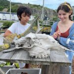 Milla Jovovich Instagram - We’re finally in Newfoundland for the last leg of @everanderson’s new movie #peterpanandwendy! We spent the day walking around the gorgeous town and had lunch at the historic @mallardcottage which was so delicious. They even have their own garden in the backyard and in the last pic you can see the way they roast meat, slow and low on hot coals made of wood from the area. Ever and her co-star @alexandermolonyofficial who plays Peter Pan had a great time finding old bones scattered around and trying to guess what each plant was growing in the garden. It’s a seaside town of charming, old houses painted in brilliant colors, sweet and friendly people and even cool vintage clothing stores. In the evening we sit downstairs at our hotel with the rest of the cast and parents playing Empire for hours! I feel so lucky to be experiencing this with my amazing kiddo! #peterpanandwendy #disney #newfoundland