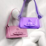 Vivienne Westwood Instagram - This season's Hazel bag features bondage-inspired elements, reminiscent of our ‘Erotic Zones' collection from Spring-Summer 1995. The pink patent finish of the Hazel is synonymous with the pink latex signage from our iconic SEX boutique, currently known as Worlds’ End. The style is also available in a Purple colourway this season, offered in both small and medium sizes.⁠
⁠
Now available online and across our boutiques. ⁠
⁠
#VWSS24