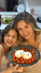 Bianca Castanho Instagram - Duas idéias de receitinhas práticas e fofas para servir como entradinha na Páscoa! 😍🐰❤️ #familiacastanhonacozinha #cozinhandocomamor #receitasdepascoa . Salada de burrata (ou mozzarela de búfala) com tomatinho cereja e manjericão. Para as orelhinhas do coelho nós cortamos a mozzarela e presunto. E para fazer os olhos e o nariz, cortamos azeitonas roxas com a ajuda de um canudo para fazer o formato redondinho. Depois é só temperar na hora de servir. Nós gostamos de temperar com azeite de oliva, flor de sal e vinagre balsâmico glaze. . Bruschetta: tostamos o pão italiano, passamos molho pesto e depois cortamos as mozzarelas de búfala em formato de coelhinho. Para finalizar cortamos o tomatinho cereja em formato de coração, decoramos com uma folha de manjericão e usamos gergelim preto para fazer os olhos e o nariz.