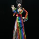 Cassandra Peterson Instagram - ANNOUNCEMENT! 🏳️‍🌈 🖤 ➖ Elvira - Over the Rainbow Elvira 8” Clothed Figure ➖ Celebrate Pride Month with Elvira, Mistress of the Dark! The devilishly delightful Cassandra Peterson has played the part of Elvira for more than 40 years with grace, humor and more than a little camp. NECA is proud to present this “Over the Rainbow” Elvira figure, celebrating the horror and queer icon in a never-before-seen, sparkling rainbow dress for your collection. With an original tailored fabric gown, glittery ruby red heels, and a yellow brick display base, she’s definitely not in Kansas anymore! This fully articulated 8-inch action figure features new faceplate technology with two interchangeable expressions and hands, including brand new ones that allow you to recreate Elvira’s signature pose! She comes with a book accessory of Peterson’s memoir, “Yours Cruelly, Elvira”, and a double-sided flag with 10 stickers to customize and show your unique pride!  ➖ Available now on thenecastore.com, and shipping to your favorite NECA retailer in June! ➖ #Elvira #MistressoftheDark #Pride #OvertheRainbow #CassandraPeterson #NECA #actionfigure