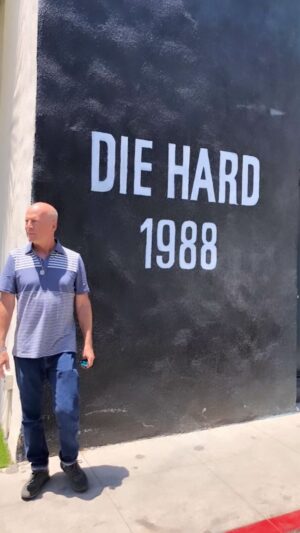 Emma Heming Instagram - Back in 2018 (when these videos and pictures were taken) we took Mabel and Evelyn to the Fox lot to peek at the archives as well as see the larger-than-life mural of their dad. 
This mural was unveiled in front of Bruce back in 2013 to commemorate Die Hard’s 25th anniversary. 
Today marks Die Hard’s 35th anniversary when it hit the screens and the rest is history. 
What Bruce has been able to accomplish in his career will never be lost on us. We are so proud of him 🤍