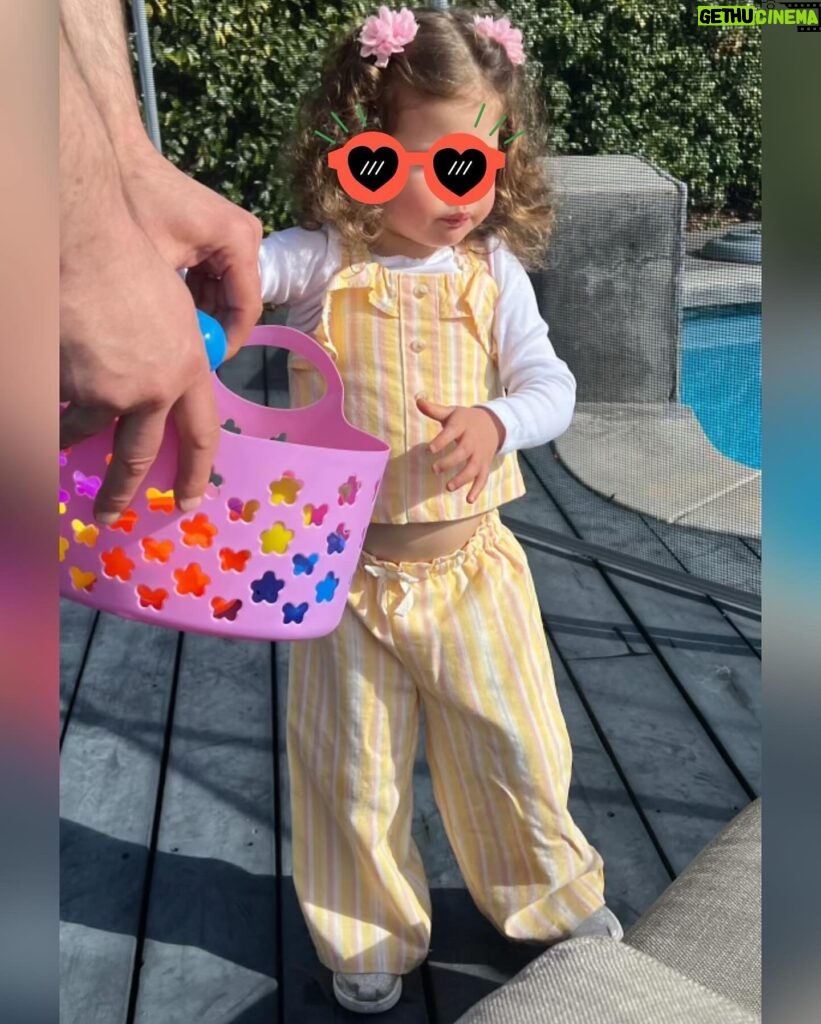 Iliza Shlesinger Instagram - We are Jewish but Sierra’s LA Grandma isn’t which means she gets Easter (and an Easter basket! I’m so jealous 🤍) and we all get Christmas. We filled eggs with Easter “candy” like… raisins and cashews and dried peaches and she had the best time. We did the neighborhood egg hunt too but she didn’t eat the chocolate because Mommy, who never lies, told her it was too spicy. Highlight for me was her holding this little blue bunny so delicately like it was a baby. Nothing will beat last year’s Easter outfit (last slide) but this one came close. 🐣🐰