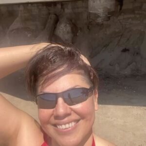 Sara Ramirez Instagram - Wishing my queer, trans, non-binary, and accomplice community a joyful and generative Pride. We are facing enraging   saddening realities and we also have each other: where we get to envisage and co-create an experience of care, love, solidarity, and joy. I’m holding space for all of our feelings and multitudes, as well as the resistance our existence continues to be. We are allowed to be imperfect, complex, messy, silly, salty, beautiful, all the rest and know our humanity matters no matter what the inaccurate projections say. We deserve to just be, today and everyday.  I love you. 
🏳️‍⚧️🏳️‍🌈💐♥️
.
.
Selfie video of Sara from the shoulders up dancing on the beach to Beyonce’s “Plastic Off the Sofa”, in a red bathing suit and black sunglasses, @trudy0nduty in a white ballcap and olive briefs, laying on a towel on the sand in the background next to a rainbow umbrella, some beach chairs and blue and white striped towels. The camera spins with a smiling Sara, the ocean waves behind them, as they play with their hair and raise their arm and hand to the sky, exhaling a revitalizing deep salty beach filled breath!