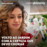 Sophie Charlotte Instagram - A PARTE 2 DE #TODASASFLORES VAI EMOCIONAR 🥹💐 O 1º capítulo da 2ª parte de #TodasAsFlores será exibido ao vivo na minha plataforma hoje, às 20h, liberado também para não assinantes. Já bota o despertador pra tocar! 😏 #PraTodosVerem: Imagem de Sophie Charlotte como Maíra na segunda parte da novela Original Globoplay, Todas as Flores. Ela tem cabelo castanho claro e comprido, com cachos largos. Dá um leve sorriso e segura uma flor branca à sua frente. Usa um colar com pedras vermelhas e uma blusa, também vermelha, com flores coloridas da gola. Texto: Volto ao jardim com a certeza que devo chorar.