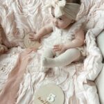Tara Lipinski Instagram - My squirmy little munchkin. Taking these month milestone pics are proving to be more difficult every month. She is all over the place! It’s her little (big) cheeks for me. I could just eat her 🍰 #babypics #5monthsold #babygirl #babylove❤️ #girlmom #newbornbaby #babycheeks