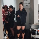 Tia-Clair Toomey Instagram - Sunday, 1:34pm: The fact that there is now a whole competition floor on the Dell Diamond concourse where a concession stand used to be — complete with 5 sets of double-under and lifting platforms, barricades and a sharp-looking @roguefitness backdrop — feels so natural, it’s easy to assume this was always the plan. It was not, but after four days of Book of Job-like weather, @caityhenniger and @billhenniger are taking no chances for the final event. Moving “The Cleanup” from the field to the concourse at the last minute is the latest example of the kind of logistical sorcery the @RogueInvitational has been performing behind the scenes all weekend. But not even Rogue can change the temperature, which dropped from 75° to 50° in the span of an hour earlier this morning. The top heat of women, the last of four heats, spend most of their 45 minute wait trying to stay warm; when @alexgazan_ 🇺🇸 takes a chair into the women’s bathroom, @laurahorvaht 🇭🇺 and @gabimiga 🇵🇱 follow suit. @tiaclair1 🇦🇺 remains outside, pacing around the warmup area with @shaneorr01’s jacket draped across her shoulders like a cape, superhero style. Shane, down to a just a longsleeve t-shirt, paces with her, shivering so hard he’s practically vibrating. A member of the Rogue event team notices, removes his own brand new Invitational hoodie and offers it to Shane, who accepts it with a mix of surprise and gratitude. By the time he pulls it on, @nick.p.jeffries is back at work, the only person on the concourse wearing shorts and a t-shirt. If you want to know what people mean when they say the Rogue Invitational goes above and beyond — it’s this. ✍🏽: @christinedca 📷: @emomphoto