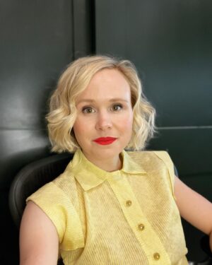 Alison Pill Instagram - Back on our zoom bullszit. #allmypunysorrows is available on demand tomorrow!  Stream it where you stream stuff.  Image description: a blonde woman in a yellow dress with red lipstick in front of a green background, second photo is a blonde dog looking up  winsomely next to a green Croc shoe.