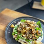 Briony May Williams Instagram – Today’s episode from my seasonal recipes series features the often overlooked, never the belle of the ball…the humble celeriac ❤️ This Spiced Celeriac on a Yogurt Flatbread is so yummy and delights the tastebuds with hints of mixed spice combined with the nuttiness of the celeriac. Trust me, it’s delicious!!! #seasontotaste

Spiced Crispy Celeriac on Yogurt Flatbread
Serves 2
Ingredients
1 celeriac
1 tbsp olive oil
1 tsp cornflour
1 tsp mixed spice
1 tsp cumin

Flatbread
200g self raising flour
200g greek yogurt

Yogurt Dressing
2 tbsp greek yogurt
1 tbsp honey/agave syrup
½ tsp mixed spice
½ tsp cumin

To serve (optional)
Salad leaves
Mixed seeds
Balsamic glaze

Method
Peel and chop the celeriac into 3cm chunks. Place in a pan of boiling water and a pinch of salt and cook for 6-7 minutes then drain.
While the celeriac is boiling, make the dough. Mix the flour and yogurt together with a generous seasoning of salt and pepper to form a soft dough. Knead for a minute then form into a ball and set aside to rest for 5 minutes.
Make the dressing by mixing the ingredients together in a bowl until combined.
Make the bread by slicing the dough in half and roll each half out on a floured surface into a circle roughly ¼ inch thick. Heat a frying pan with a drizzle of olive oil, once hot add the dough and cook for 3 minutes then flip and cook the other side for a further 3 minutes. Cook until each side is golden brown and the bread is cooked through. Repeat with the other half of the dough. 
Place the drained celeriac in a bowl and drizzle over the olive oil. Mix. Combine the cornflour, mixed spice and cumin then sprinkle over the celeriac and mix well to coat. Heat a drizzle of olive oil in a pan, once hot add the coated celeriac and cook for 10-15 minutes until crispy on the outside and tender on the inside.
Place flatbread on a serving dish. Spread over half the dressing, top with salad leaves and the crispy celeriac. Drizzle over the balsamic glaze, sprinkle the seeds then enjoy!

#seasonal #season #celeriac #recipe #yummy #delicious #easycooking #easymeals #healthy #vegetarian #vegan #plantbased #lunchideas #lunch #bread #flatbread