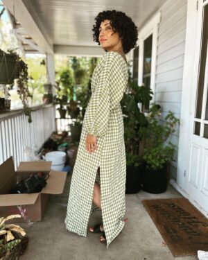 Jasika Nicole Instagram - Savage calls this dress 🎶GinghnamStyle🎶 and I am calling it 🥒 The Pickle Dress🥒- both are pretty accurate! I was inspired by a checked Mara Hoffman wrap dress that floated across my Pinterest once and couldn’t get out of my head. I planned on hacking several different patterns together to make it but luckily a fellow instagrammer reached out to show me McCalls 8035 which would be a way closer twin to the Mara Hoffman garment with only a few tweaks. I ended up using the bodice sleeves of the Elodie dress by @closetcorepatterns instead of the set in sleeves of the McCalls because I ❤️adore❤️ that subtle little shoulder peeking out and I knew I could achieve this best with a grown on sleeve. I also adjusted the back bodice piece to have a V-neck line at the back to give the sleeve more space to dip off the shoulder. I changed the waistline of the bodice and skirt to accommodate a wider piece of elastic like the inspo dress (I used 1.5” wide elastic), zigzagged across the elasticized waistband to make it more stable, added some elastic to the sleeve hems and finally I stuck a bra strap holder to the shoulder seam so that when I wore it off my shoulder my bra strap wouldn’t try and creep into frame. My sleeves have slightly more drama and the skirt is a touch more billowy than the inspo but all in all I think I nailed this hack. It includes all the markers of what I initially loved about the inspo dress- a fun graphic print ✅ in a color I love ✅ in linen, a fabric I love (this gingham is gifted from @wearethefabricstore and is very excellent) ✅, with a romantic, flowy silhouette ✅ that looks great with this hair length lol ✅ I tried to recreate the inspo photo in front of our white garage door but it was so bright outside that the pics came out grainy- hopefully the vibes still translate 💚