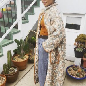 Jasika Nicole Instagram - I didn’t hop onto the quilted jacket trend til @byhandlondon released the #NerrisaCoat pattern a couple months ago. I loved the collar, the oversized fit and the long length, three elements that I had not previously seen in quilted coat patterns, and I had the *perfect* fabric for it- a geometric reversible quilted cotton smack in the middle of my color palette from @corefabrics. The pattern is very simple, pretty beginner friendly, and requires very little fit adjusting because it’s so oversized. I made the smallest size available (it goes up to a size E/ 61.75” bust) but it’s still incredibly roomy, like I could probably fit a sweater AND another coat under this lol. If I were to make it again I would probably slim down the fit by a couple inches and shorten it to shin length, which I might still do, but I wanted to get some wear out of this length before I chopped it up. I opted not to add buttons to the front and just have this be a kind of open jacket for layering. I made the bias binding myself and this is the only issue I had with the pattern- it says you need 5 meters of binding but I easily used 3 times that much for this view (I stopped counting after the third time I had to pull out my tools to make more tape 😵‍💫), so maybe that amount was meant for the shorter version of the jacket (because it doesn’t give different amounts for the different views). Thankfully I had just enough tencel scrap fabric to make all the tape I needed. The bias binding gives the jacket a nice pop of color while still feeling a bit neutral and I love how the colors in the fabric and tape play off of each other. I’m on the fence about the patch pockets on my version and think it would look even better with inset pockets, and because of the bulk of the quilted fabric, the drop sleeves look a little funky at the seams(I prefer inset sleeves). But those design choices are what makes this such a simple and quick pattern to finish, and I’m still happy with how this came out. The fabric is structured but soft and wearing it feels like you’re draped in a blanket cocoon- it actually makes a pretty great housecoat if you’re careful to not trip over it 😂