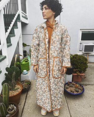 Jasika Nicole Instagram - I didn’t hop onto the quilted jacket trend til @byhandlondon released the #NerrisaCoat pattern a couple months ago. I loved the collar, the oversized fit and the long length, three elements that I had not previously seen in quilted coat patterns, and I had the *perfect* fabric for it- a geometric reversible quilted cotton smack in the middle of my color palette from @corefabrics. The pattern is very simple, pretty beginner friendly, and requires very little fit adjusting because it’s so oversized. I made the smallest size available (it goes up to a size E/ 61.75” bust) but it’s still incredibly roomy, like I could probably fit a sweater AND another coat under this lol. If I were to make it again I would probably slim down the fit by a couple inches and shorten it to shin length, which I might still do, but I wanted to get some wear out of this length before I chopped it up. I opted not to add buttons to the front and just have this be a kind of open jacket for layering. I made the bias binding myself and this is the only issue I had with the pattern- it says you need 5 meters of binding but I easily used 3 times that much for this view (I stopped counting after the third time I had to pull out my tools to make more tape 😵‍💫), so maybe that amount was meant for the shorter version of the jacket (because it doesn’t give different amounts for the different views). Thankfully I had just enough tencel scrap fabric to make all the tape I needed. The bias binding gives the jacket a nice pop of color while still feeling a bit neutral and I love how the colors in the fabric and tape play off of each other. I’m on the fence about the patch pockets on my version and think it would look even better with inset pockets, and because of the bulk of the quilted fabric, the drop sleeves look a little funky at the seams(I prefer inset sleeves). But those design choices are what makes this such a simple and quick pattern to finish, and I’m still happy with how this came out. The fabric is structured but soft and wearing it feels like you’re draped in a blanket cocoon- it actually makes a pretty great housecoat if you’re careful to not trip over it 😂